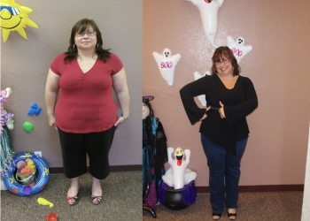 A woman is standing in front of a wall with her arms around herself.